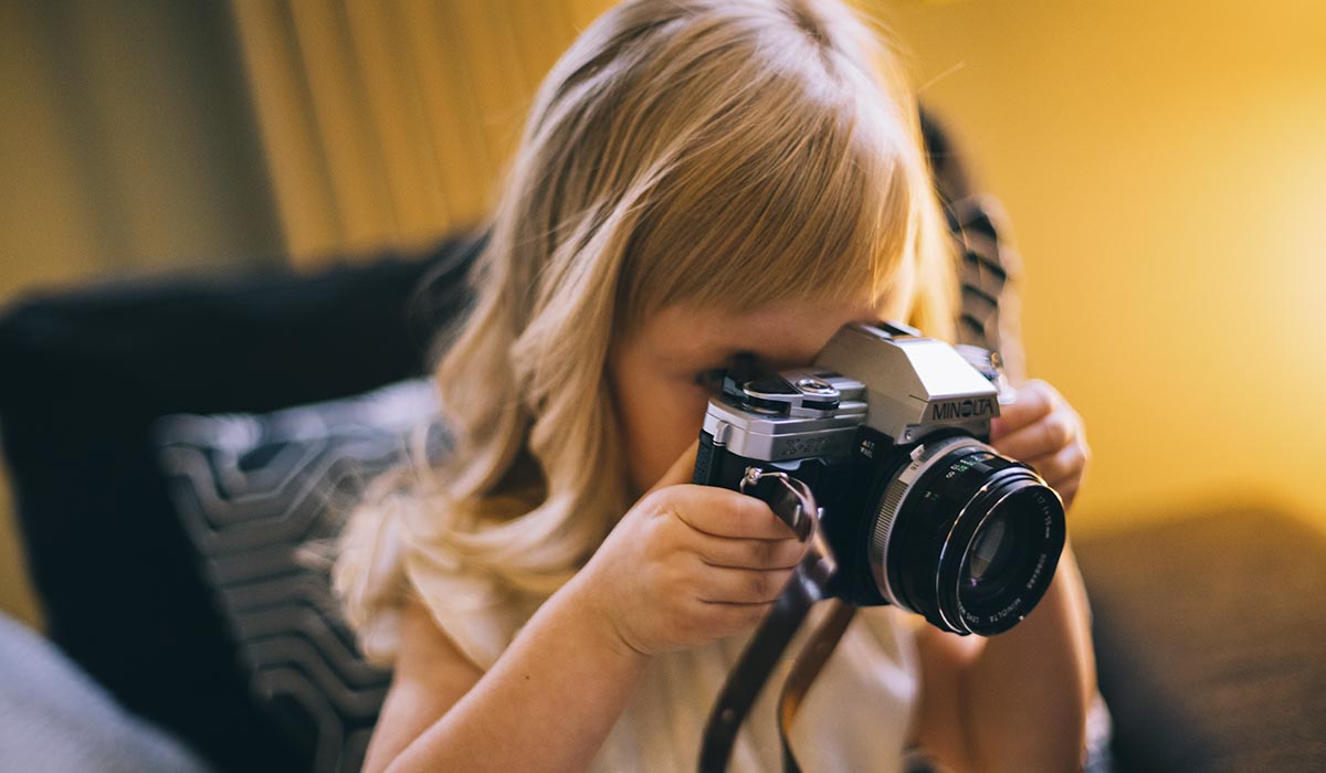 Bambina che scatta una fotografia con una reflex