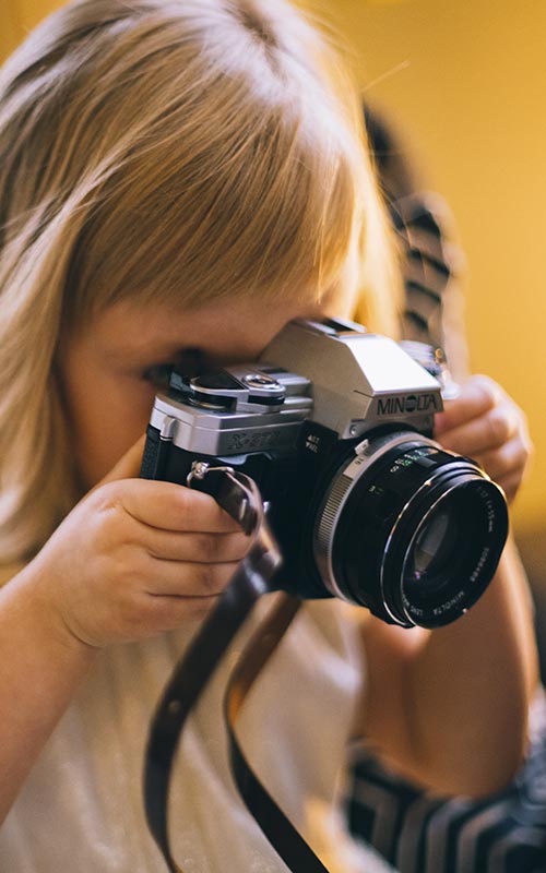 Bambina che scatta una fotografia con una reflex